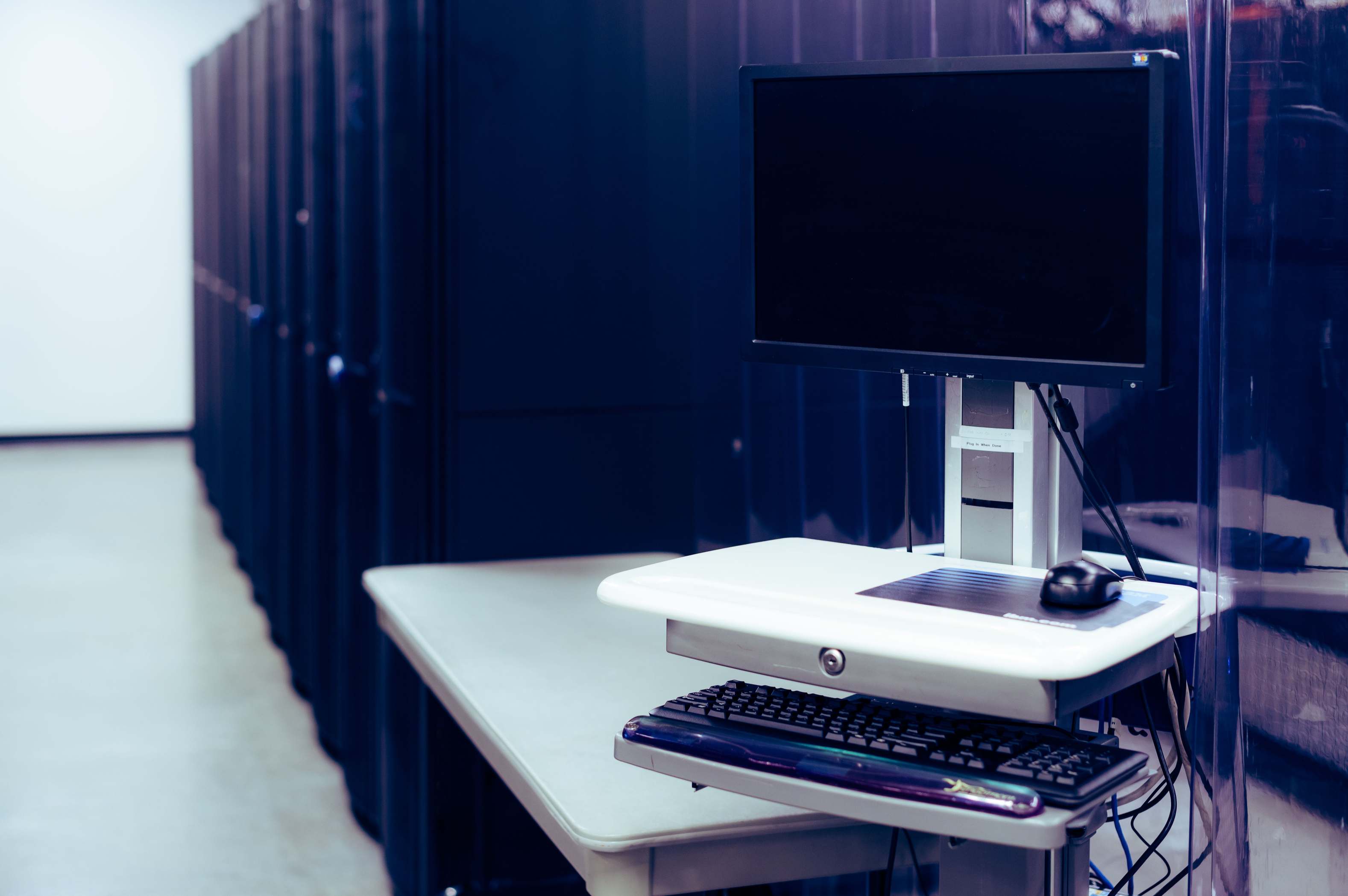 Wide view of server equipment in a data facility with computer near server racks in data center